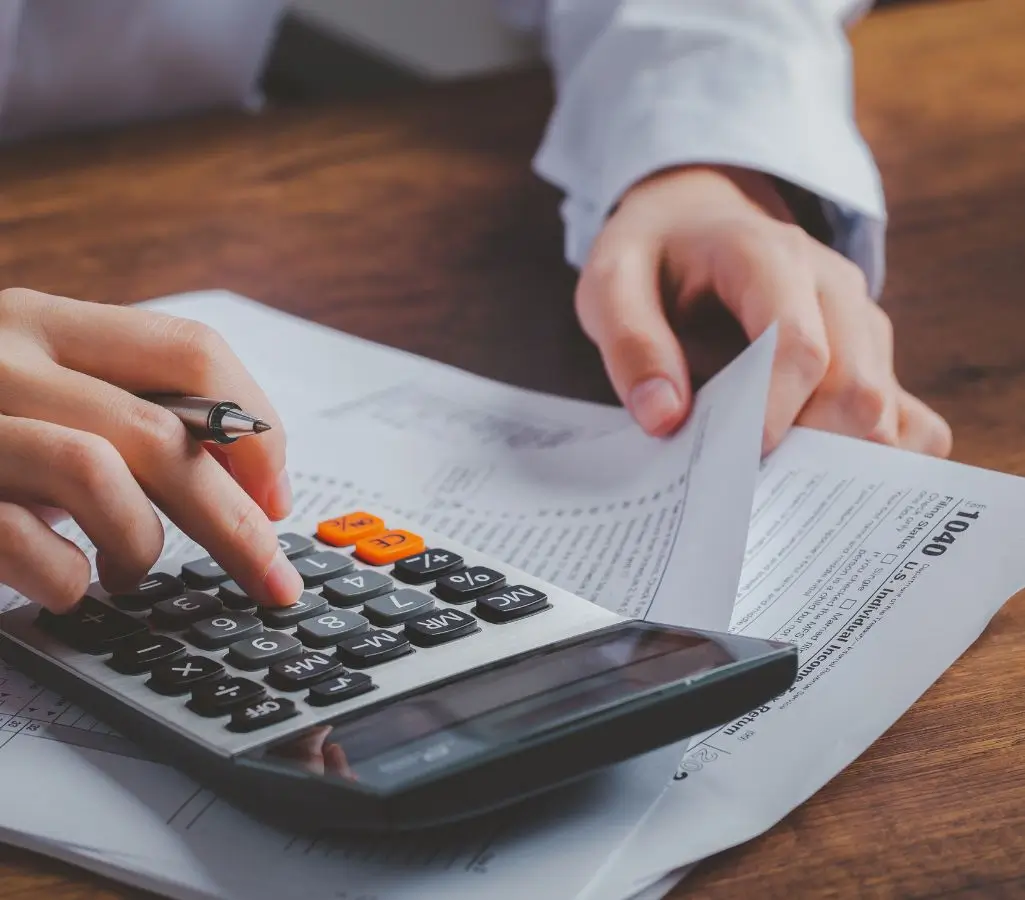 Renta socjalna. Poradnik o świadczeniu z ZUS dla niepełnosprawnych? 1 Obrazek wyróżniający w artykule renta socjalna. Dłoń z długopisem wystukuje na kalkulatorze, druga dłoń trzyma dokumenty. Obrazek sugeruje obliczanie wysokości renty socjalnej lub wnioskowanie o nią.